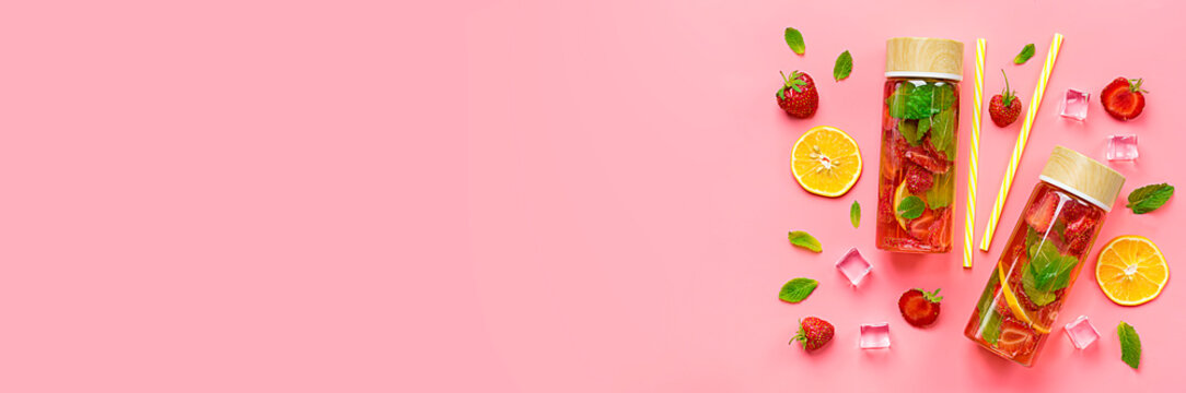 Strawberry infused water, cocktail, lemonade or tea. Summer iced cold drink with strawberry, lemon and lef of mint on pink background. Flat lay. Top view. Banner