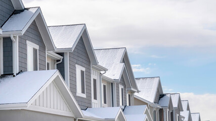 Panorama crop Facade of snowy townhouses in South Jordan Utah against cloudy sky in winter