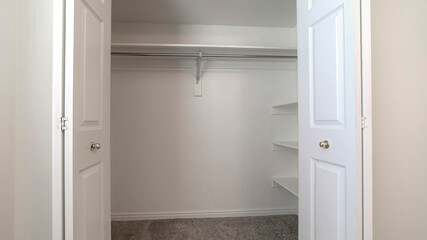 Panorama Walk in closet with double hinged doors plain white wall and gray floor carpet