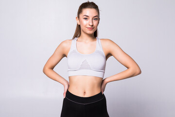 Fototapeta na wymiar Tough young woman standing on grey background. Muscular female looking at camera. Female bodybuilder wearing gloves ready for gym exercise.