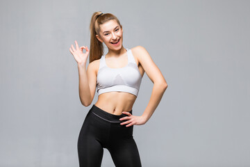 Fototapeta na wymiar Attractive woman with okay in gym attire in her outstretched arms isolated on white background