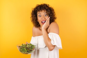 Surprise astonished beautiful girl looking surprised in full disbelief wide open mouth with hand near face. Positive emotion facial expression body language.