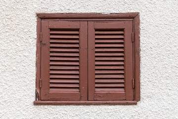 Closed window with brown shutters on a light wall, Cyprus
