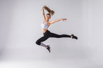 Happy young fitness woman jumping over white background