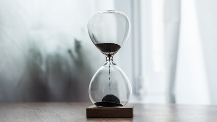 Sandglass timer on a wood table, center