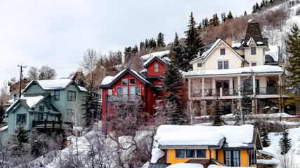 Panorama Snow covered hill brightened by colorful homes and lush evergreens in winter
