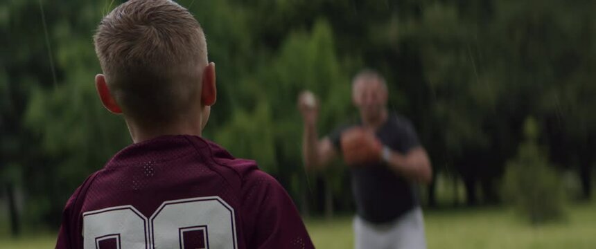 MED Father and son playing baseball catch in the park on a rainy day. Family time spent together. Shot with 2x Anamorphic lens