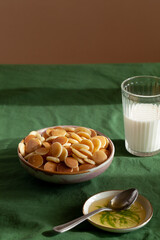 Bowl with tiny pancake cereal porridge on a green textile background with copy space.Trendy tasty breakfast food