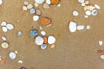 Beautiful beach sand background with pebbles. Brown sandy texture with stones. Summer concept. Top view.