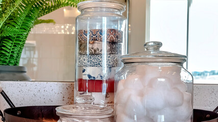 Panorama frame Jars of soap cotton balls and buds on metal tray beside potted leafy green plant