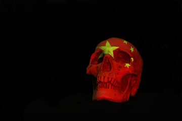 A white skull isloated aginst a plain black background with the Chinese National Flag projected over it.