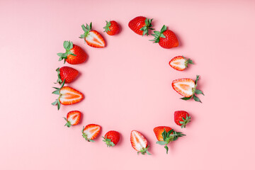 round frame made of fresh tasty strawberries on a pink background. Beautiful background or greeting card. copy space, flat lay, border.