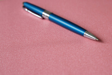 Metallic blue ballpoint pen on a pink background. Background and texture for designer