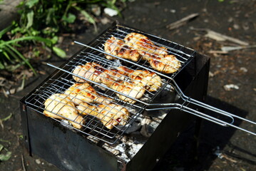 chicken legs are grilled on the grill in nature