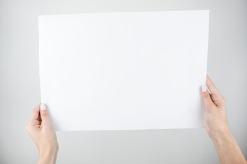 woman's hands holding banner sign with white blank empty paper billboard with copy space for text over gray background