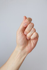 Gesture and sign, male hand holds something on a light background