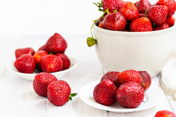 Large ripe strawberries are collected from the garden. On a white wooden background. Homemade winter fruit blanks. Selective focus.