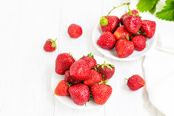 Large ripe strawberries are collected from the garden. On a white wooden background. Homemade winter fruit blanks. Selective focus.