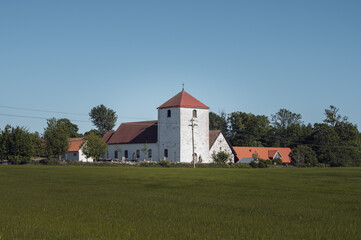 Fototapeta na wymiar The medieval Fulltofta church stand close to the agricultural fields in the flat farmlands of Skåne (Scania) in southern Sweden