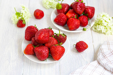 Large ripe strawberries are collected from the garden. On a white wooden background. Homemade winter fruit blanks. Selective focus.