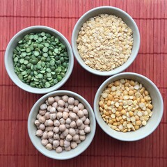 Round bowls with legumes, peas, chickpeas and lentils on a red background. A bowl of food on a plate. High quality photo