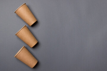 Three eco-friendly cardboard cups lie on a gray background with copy space. Mock-up. Close-up. The concept of ecology