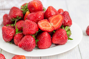 Large ripe strawberries are collected from the garden. On a white wooden background. Homemade winter fruit blanks. Selective focus.