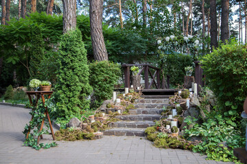 Obraz premium A delightful composition using moss in a rustic style to decorate the stairs, log cuts are located along the stairs, white candles in glass vases.