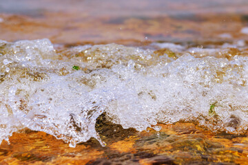 Sea waves over colorful rocks and stones. Selective focus.