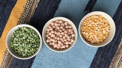 Bowl with legumes stand on a woven multi-colored tablecloth. Gastronomic background for decoration and design of the kitchen, dining room, shop, restaurant.