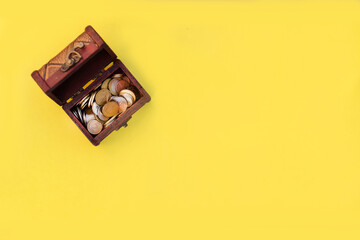 rustic treasure chest with coins on yellow background