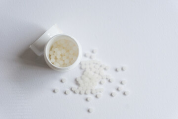 Homeopathy pills in a pot and spread on the surface. Medical concept.