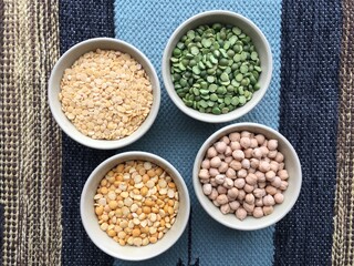 Bowl with legumes stand on a woven multi-colored tablecloth. Gastronomic background for decoration and design of the kitchen, dining room, shop, restaurant.