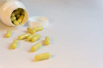 White pot of green pills. Pills spread on