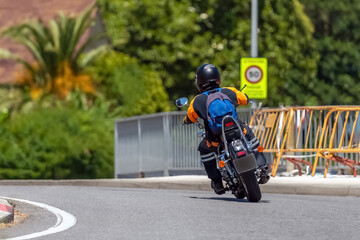 motorcyclist goes through a turn on a city road, rear view