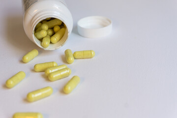 White pot of green pills. Pills spread on