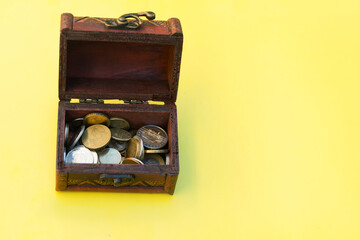rustic treasure chest with coins on yellow background