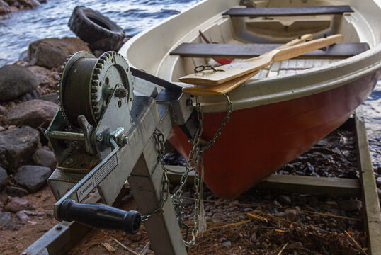 A red rowing boat (oar boat) on a slipway with a winch on lake shore in Finland