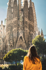 Barcelona, Spain - Tourist woman or girl looking at the church La Sagrada Familia. It is designed by architect Antonio Gaudi and is being build since 1882.