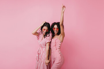 Sensual african lady having fun with her best friend. Indoor photo of adorable girls in pink clothes standing on light background