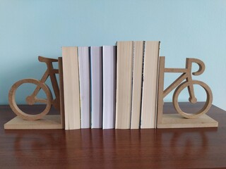 Książki na półce z podpórką w kształcie roweru - obrazy, fototapety, plakaty
