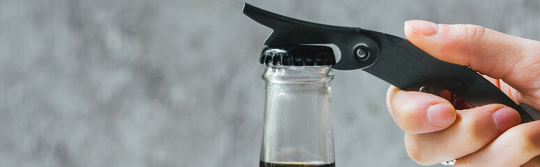 cropped view of woman opening cold brew coffee in bottle with opener, panoramic shot
