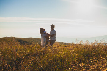 Mother and father holding their little son in summer meadow