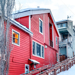 Square frame Outdoor stairs and cozy houses on a snowy hill against cloudy sky in winter