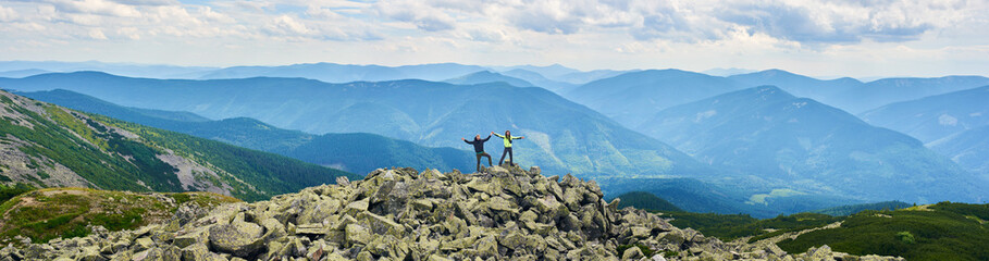 Panoramic view of loving couple holding hands up beautiful mountains scenery on background....