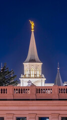 Vertical crop Provo City Center Temple with statue of angel and spire against blue evening sky