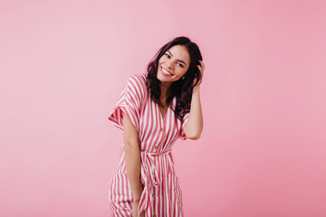 Spectacular latin young woman playing with her brown hair. Indoor photo of wonderful female model isolated on pink background