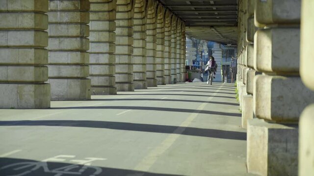 Woman on a bicycle crossing a Parisian bridge at sunrise