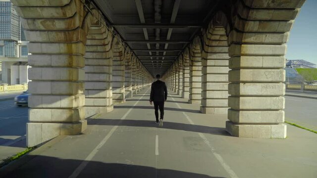 Single man crossing a Parisian bridge. Sunset on the Bercy bridge
