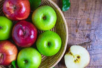 .Green apple and red apple in a basket on a wooden background